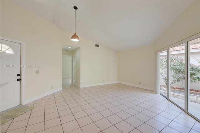 spare room with vaulted ceiling, light tile patterned floors, visible vents, and baseboards