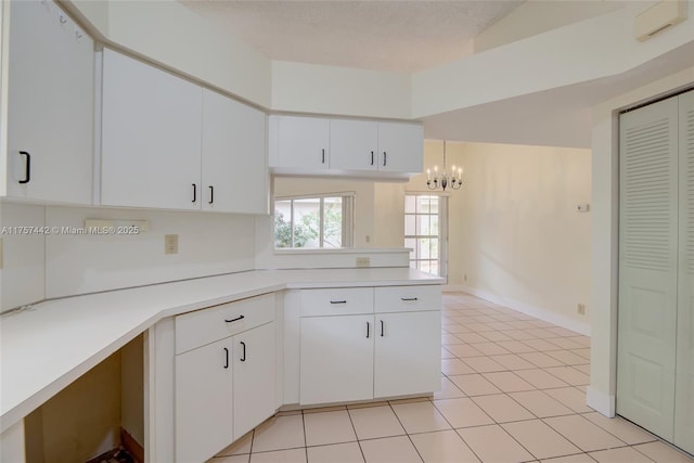 kitchen featuring white cabinets, a peninsula, light countertops, a textured ceiling, and light tile patterned flooring