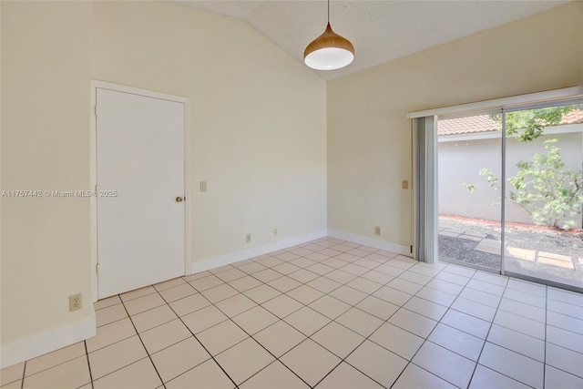 empty room featuring lofted ceiling, light tile patterned floors, and baseboards