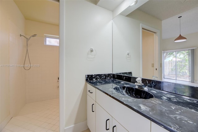 bathroom with a wealth of natural light, tiled shower, and vanity