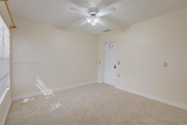 spare room featuring a textured ceiling, light carpet, visible vents, and baseboards