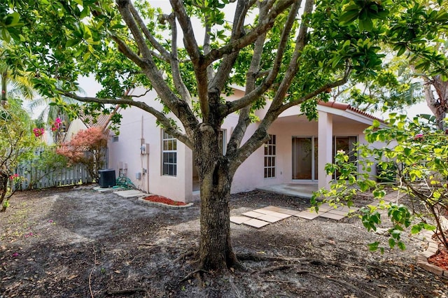 back of house featuring fence, cooling unit, and stucco siding