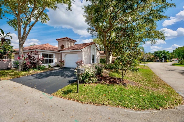 mediterranean / spanish-style home featuring a garage, stucco siding, a tiled roof, and aphalt driveway