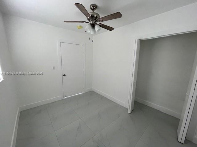 spare room featuring marble finish floor, a ceiling fan, and baseboards