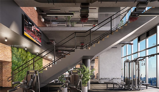 stairs featuring expansive windows, brick wall, and a towering ceiling