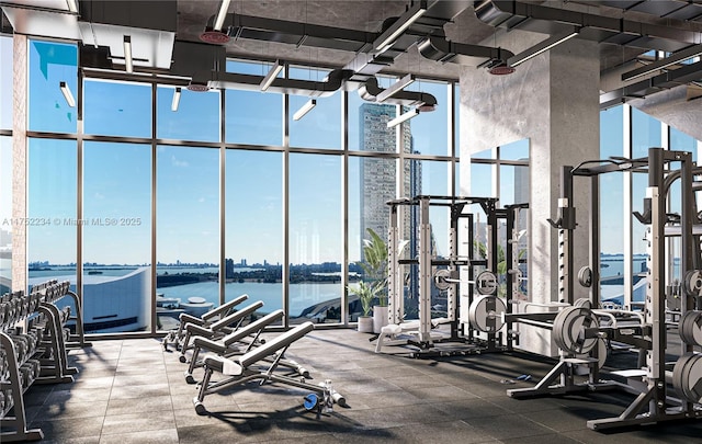 gym with expansive windows, a water view, and a healthy amount of sunlight