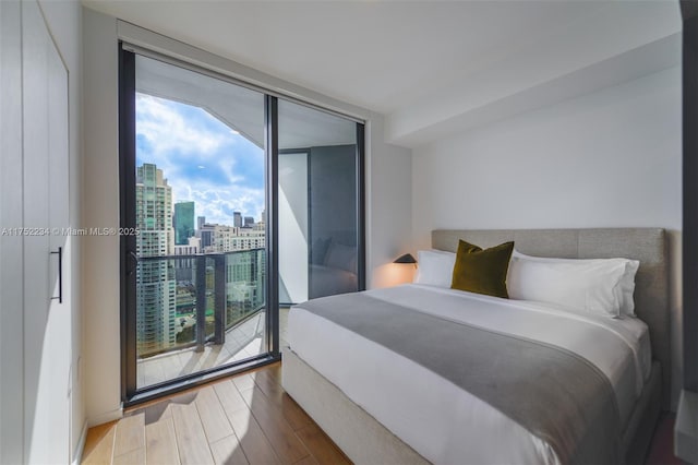 bedroom featuring a view of city, expansive windows, and wood finished floors