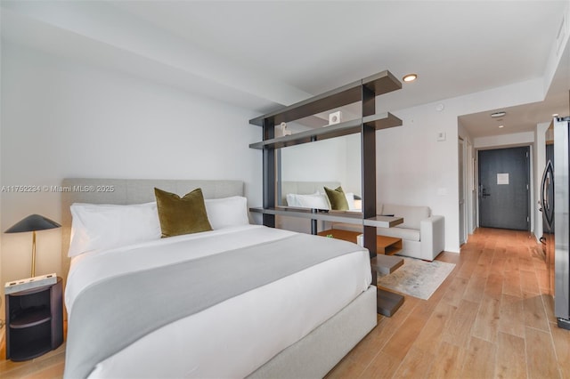 bedroom with freestanding refrigerator, light wood finished floors, and recessed lighting