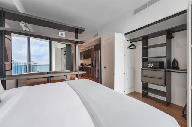 bedroom featuring visible vents, wood finished floors, and stainless steel fridge with ice dispenser