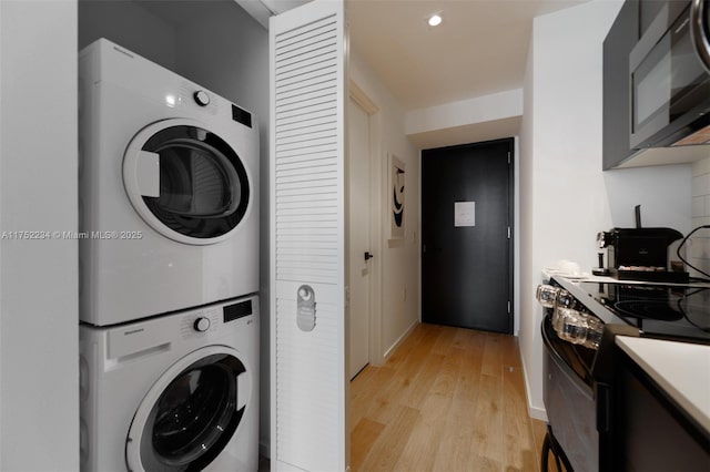 laundry area featuring laundry area, stacked washer and clothes dryer, and light wood-style floors