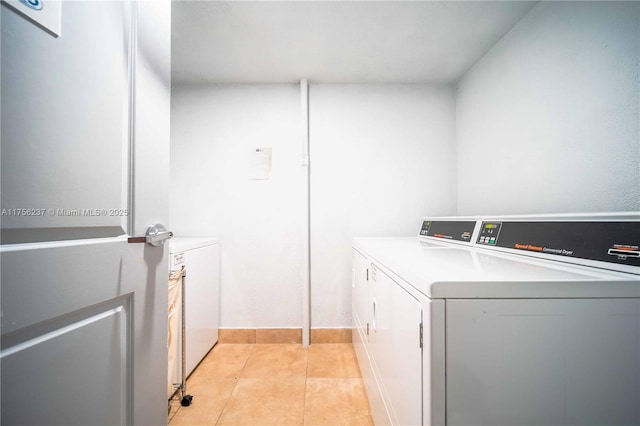 shared laundry area with washer and dryer and light tile patterned floors