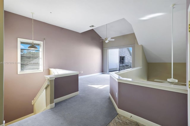 hallway featuring lofted ceiling, visible vents, an upstairs landing, baseboards, and carpet