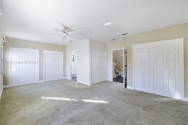 unfurnished bedroom with multiple closets, visible vents, and carpet flooring