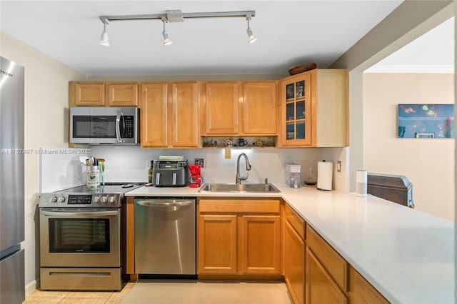 kitchen featuring stainless steel appliances, light countertops, a sink, and glass insert cabinets