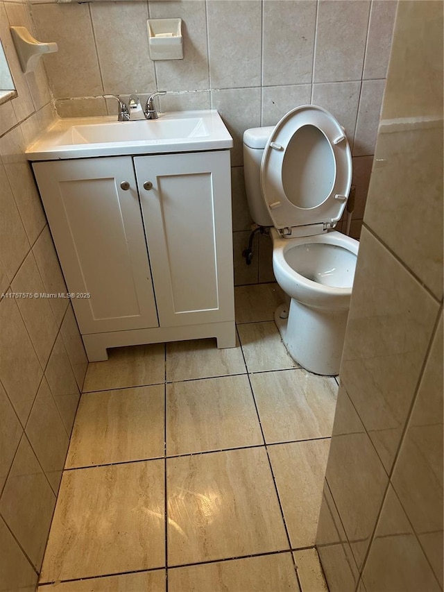 bathroom featuring tile walls, toilet, tile patterned floors, vanity, and backsplash