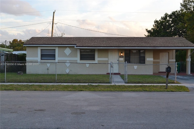 view of front facade with a fenced front yard, a front yard, a shingled roof, and stucco siding