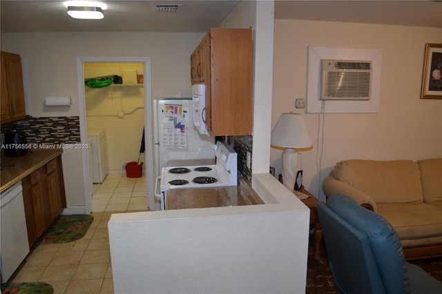 kitchen featuring white appliances, light tile patterned floors, visible vents, decorative backsplash, and an AC wall unit