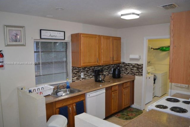 kitchen with a sink, visible vents, washer and dryer, decorative backsplash, and dishwasher