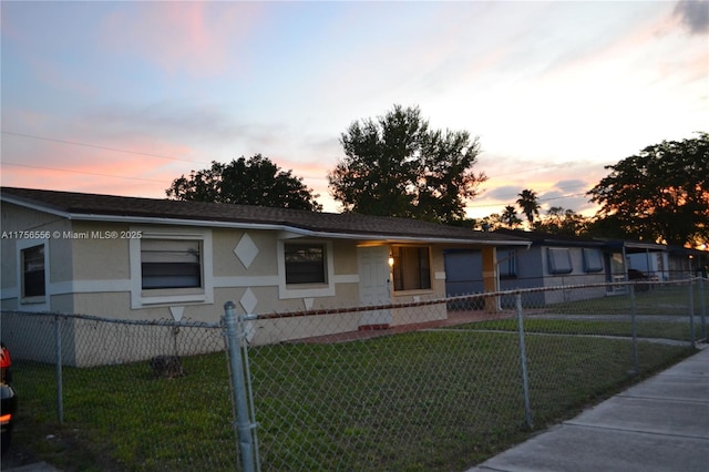 view of front of home with stucco siding, a fenced front yard, and a yard