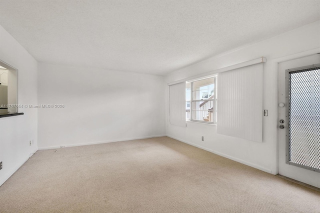 carpeted empty room with a textured ceiling and baseboards