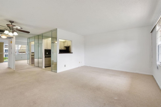 empty room featuring ceiling fan, a textured ceiling, and light colored carpet