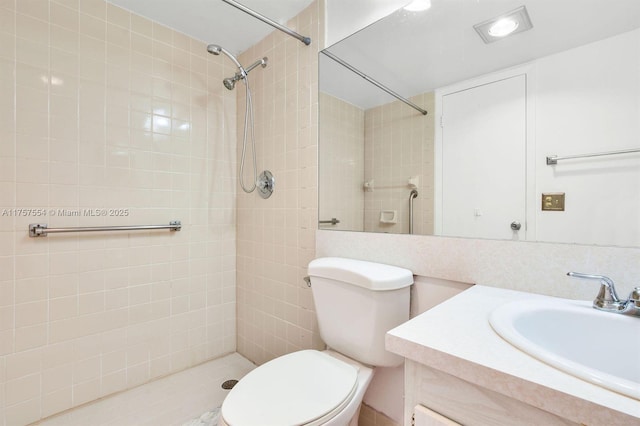 full bathroom featuring tiled shower, vanity, and toilet