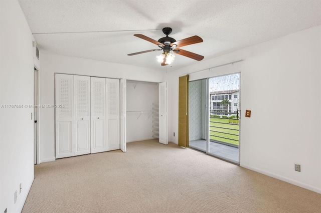 unfurnished bedroom with access to exterior, carpet, and two closets