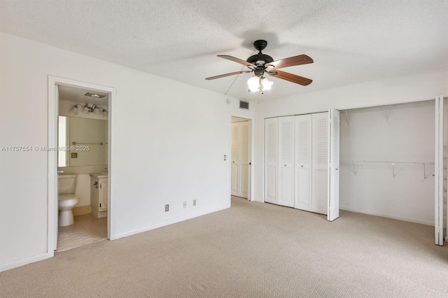 unfurnished bedroom featuring a textured ceiling, carpet flooring, visible vents, and multiple closets