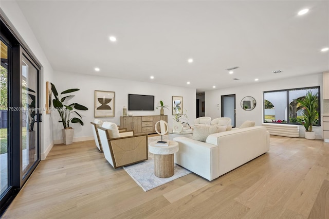 living area with light wood finished floors, plenty of natural light, baseboards, and recessed lighting