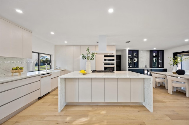 kitchen with white appliances, light wood-style floors, a large island, backsplash, and modern cabinets