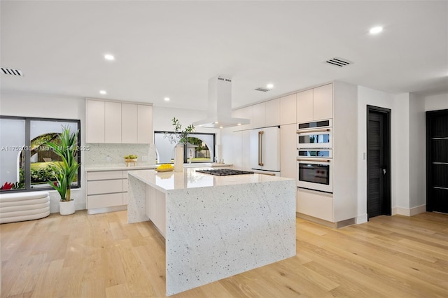 kitchen featuring a kitchen island, modern cabinets, island exhaust hood, and visible vents