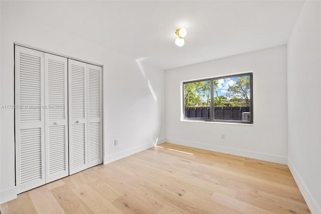 unfurnished bedroom featuring a closet, baseboards, and wood finished floors