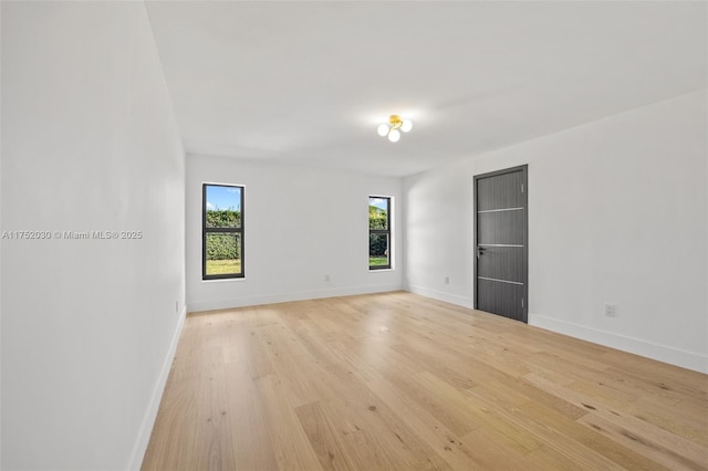 spare room featuring light wood-type flooring and baseboards