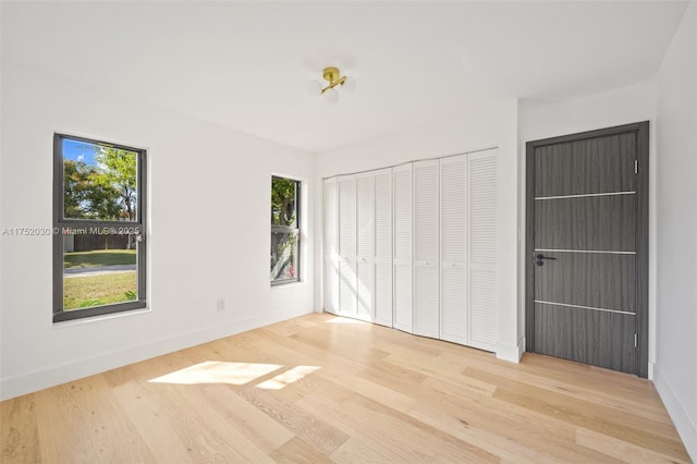 unfurnished bedroom featuring a closet, baseboards, and wood finished floors