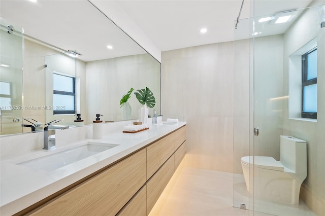 bathroom with toilet, double vanity, an enclosed shower, and a sink