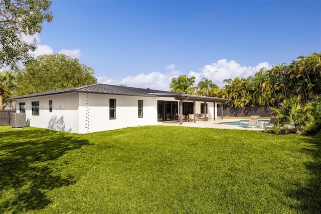 rear view of property featuring a standing seam roof, a patio area, a lawn, and cooling unit