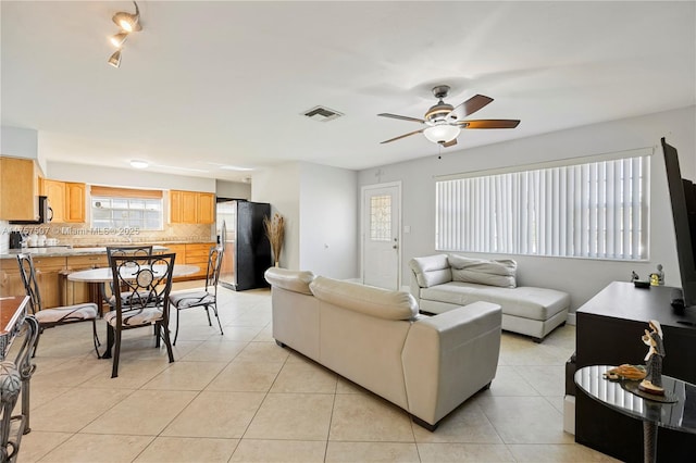 living area featuring light tile patterned floors, visible vents, and a ceiling fan