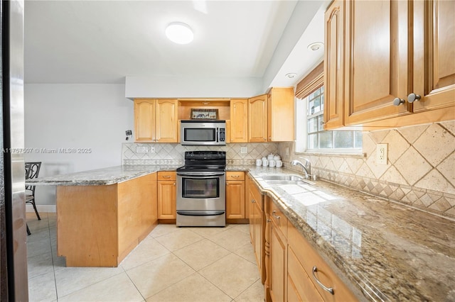 kitchen with light tile patterned floors, light stone counters, a peninsula, stainless steel appliances, and a sink