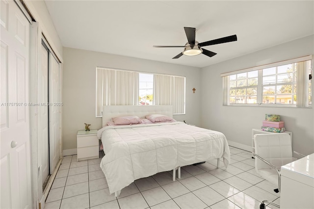 bedroom featuring light tile patterned floors, a closet, baseboards, and a ceiling fan