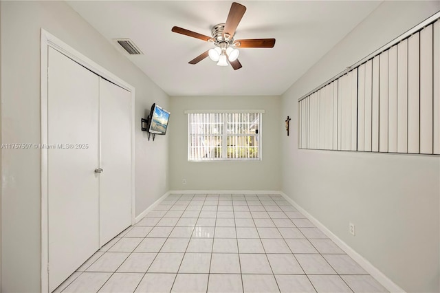 spare room featuring light tile patterned floors, visible vents, baseboards, and a ceiling fan