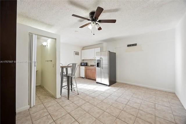 kitchen featuring a ceiling fan, a textured ceiling, light tile patterned flooring, stainless steel fridge with ice dispenser, and baseboards