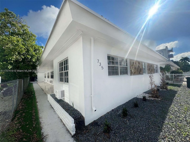 view of home's exterior with fence and stucco siding