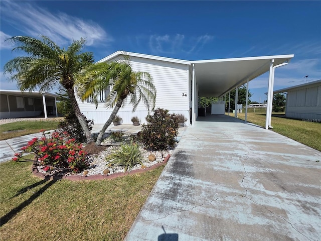 view of side of property with a lawn, an attached carport, and concrete driveway