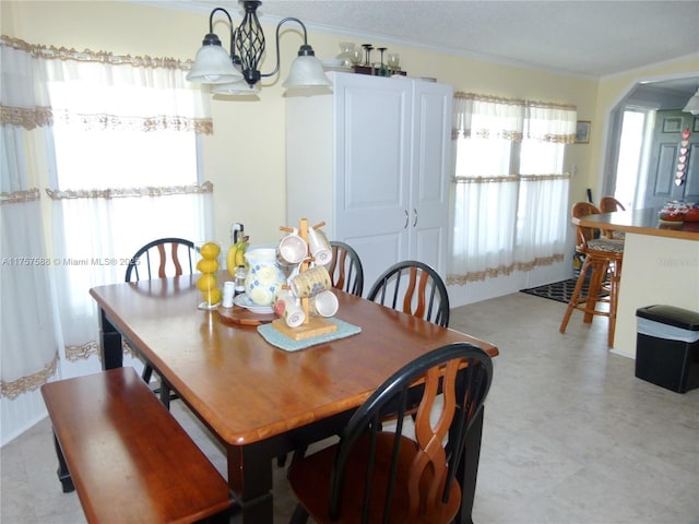 dining space with light floors, arched walkways, and crown molding