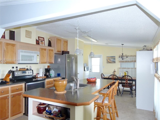 kitchen featuring appliances with stainless steel finishes, dark countertops, a sink, and a kitchen island with sink