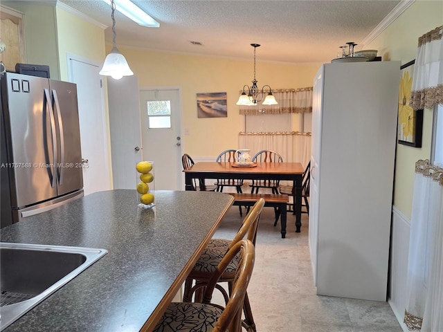 kitchen featuring dark countertops, ornamental molding, freestanding refrigerator, and decorative light fixtures