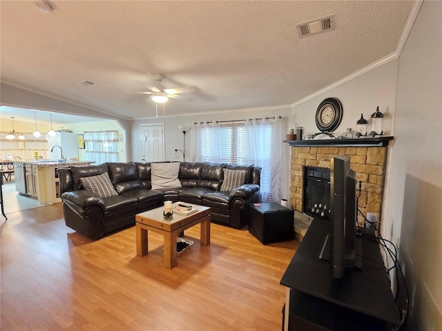 living room with light wood-style floors, crown molding, a ceiling fan, and visible vents
