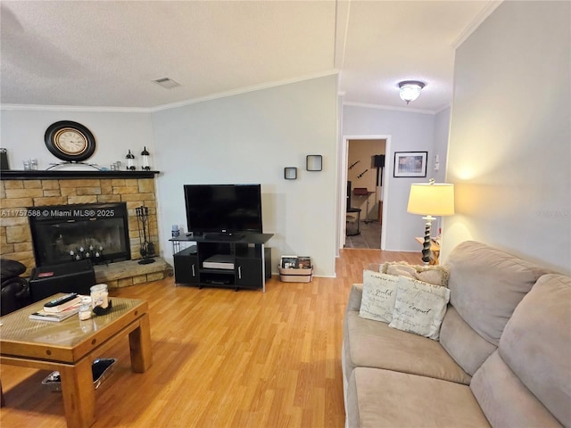 living room with crown molding, a fireplace, wood finished floors, and visible vents
