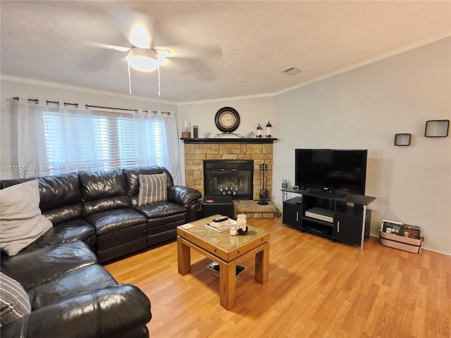 living area featuring a ceiling fan, a stone fireplace, ornamental molding, and wood finished floors