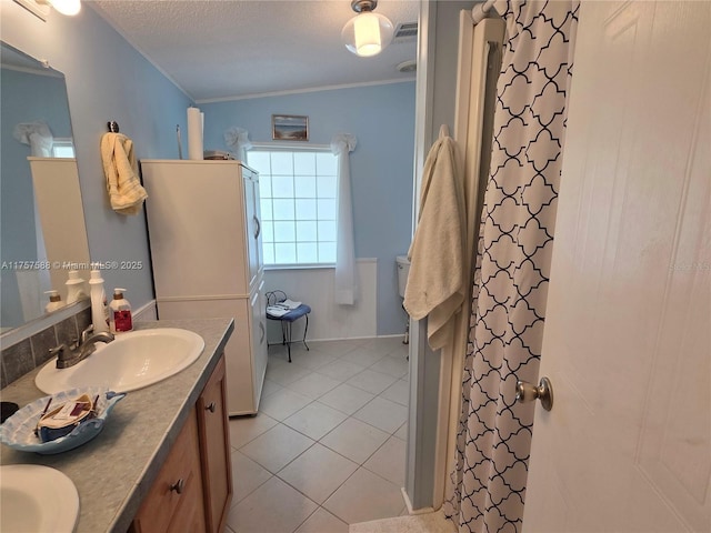 bathroom with double vanity, a textured ceiling, crown molding, tile patterned flooring, and a sink